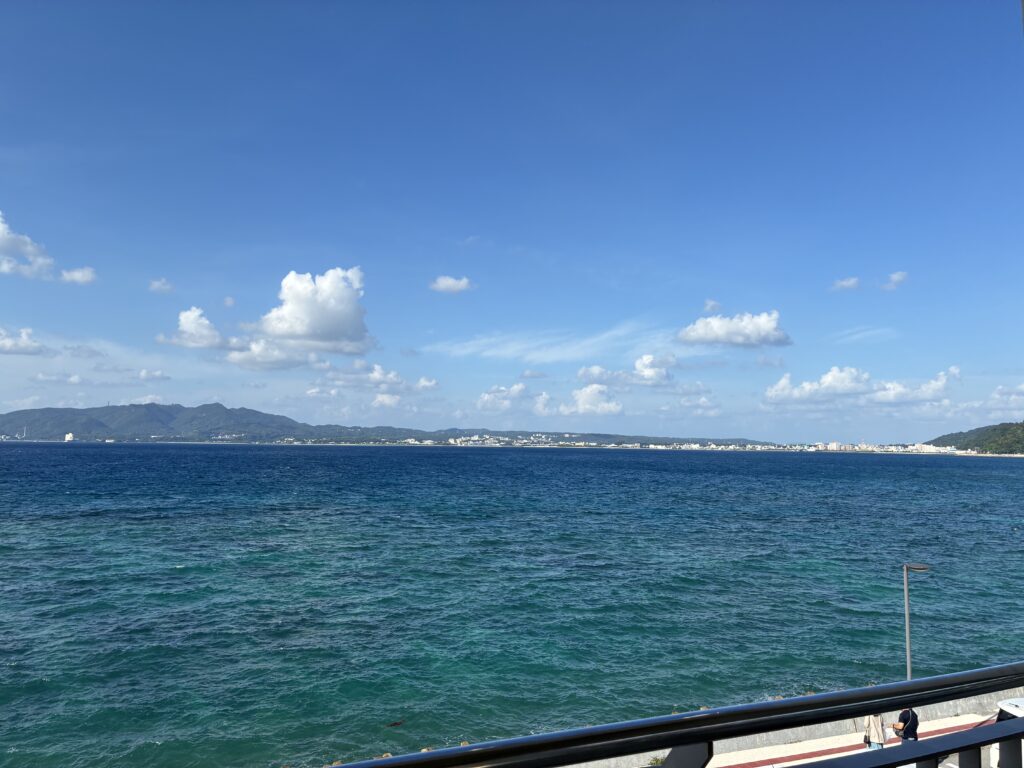11月の沖縄本島北部・道の駅許田から望む海と本部半島の山並み。深い青の海と秋の青空が広がる絶景