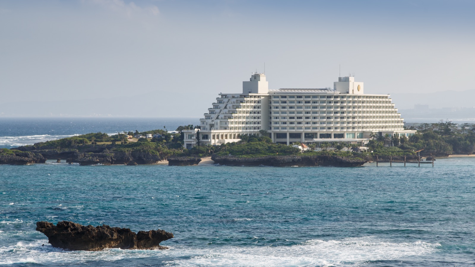 沖縄本島・恩納村のANA万座ビーチリゾート。青い海と岬に建つ大型リゾートホテルの明るい風景