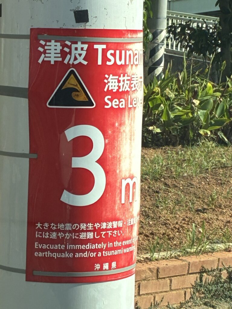 沖縄県が電柱に設置した津波・海抜表示。海抜3mと表示され、地震や津波警報の際は速やかに避難するよう日本語と英語で書かれている